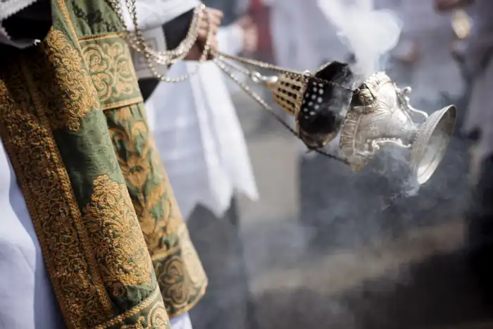 Priest holding lanterns of frankincense