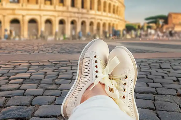 feet with shoes with colosseum in the background