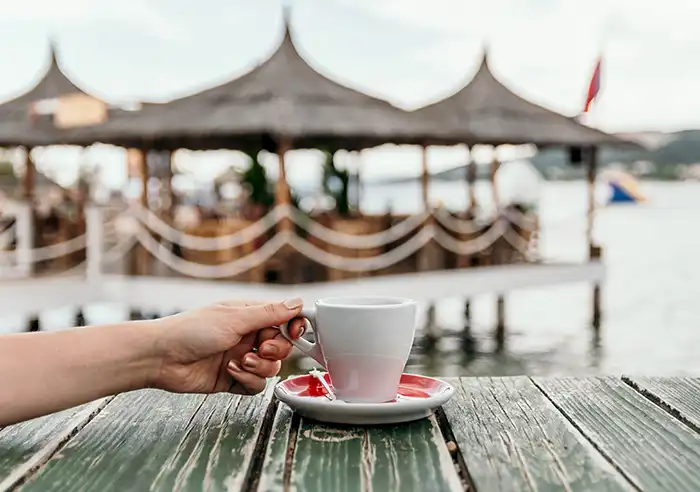 hand with espresso near the sea
